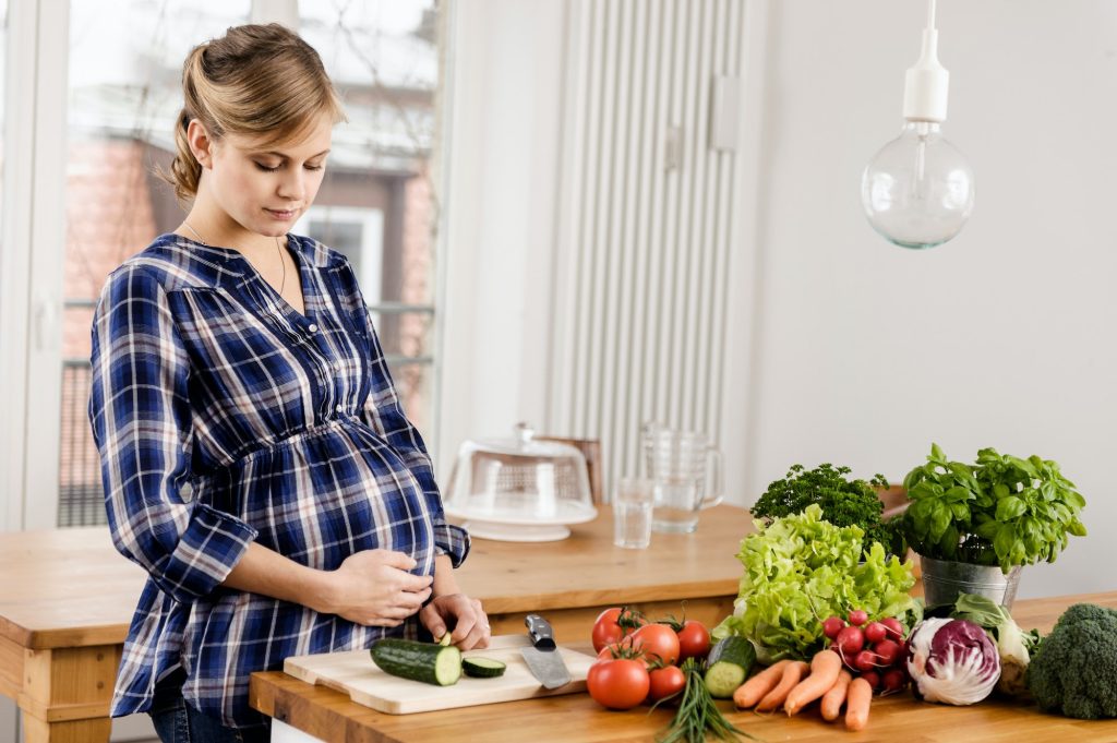 kobieta w ciąży, która zmienia pozycję, aby zapobiec cofaniu się treści żołądkowej do przełyku, co jest jednym ze sposobów łagodzenia objawów zgagi w ciąży.