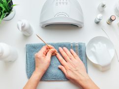 Woman preparing nails to apply gel hybrid polish using UV lamp. Beauty wellness treatment concept