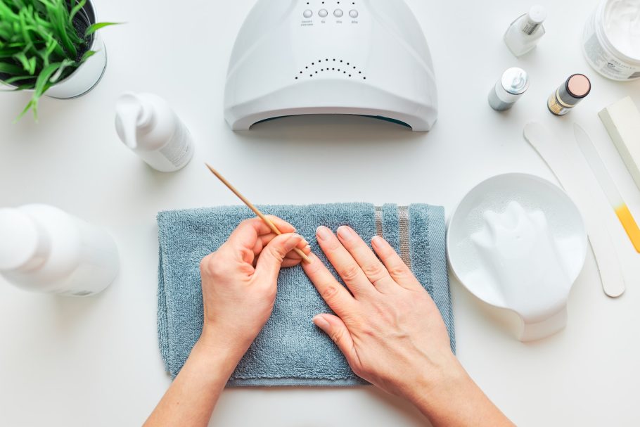 Woman preparing nails to apply gel hybrid polish using UV lamp. Beauty wellness treatment concept