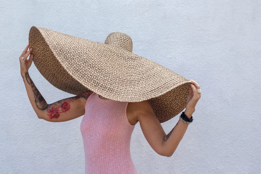 Beautiful woman in big beach straw hat and pink dress. summer vacation time. Beach accessory